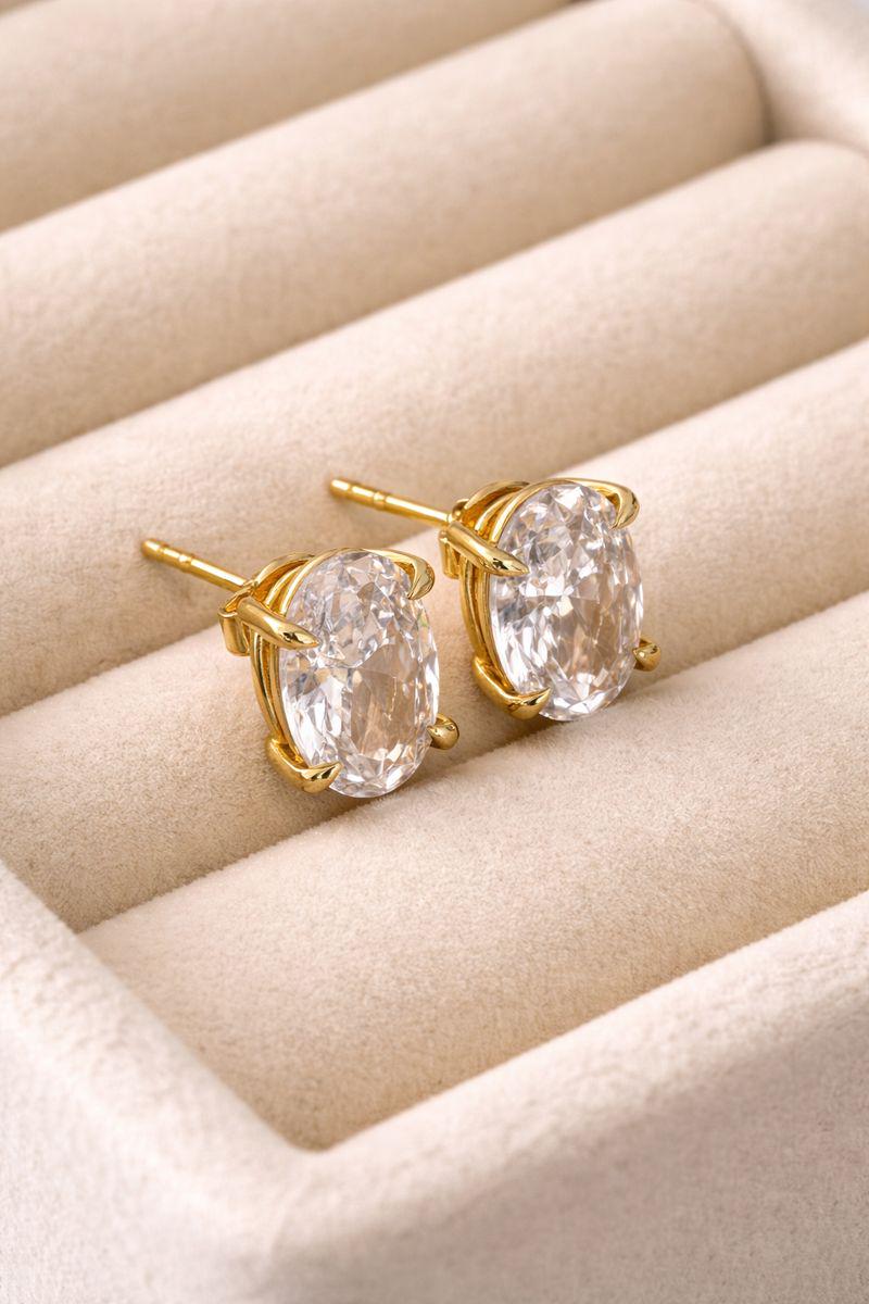Gold oval CZ solitaire stud earrings shown close-up.
