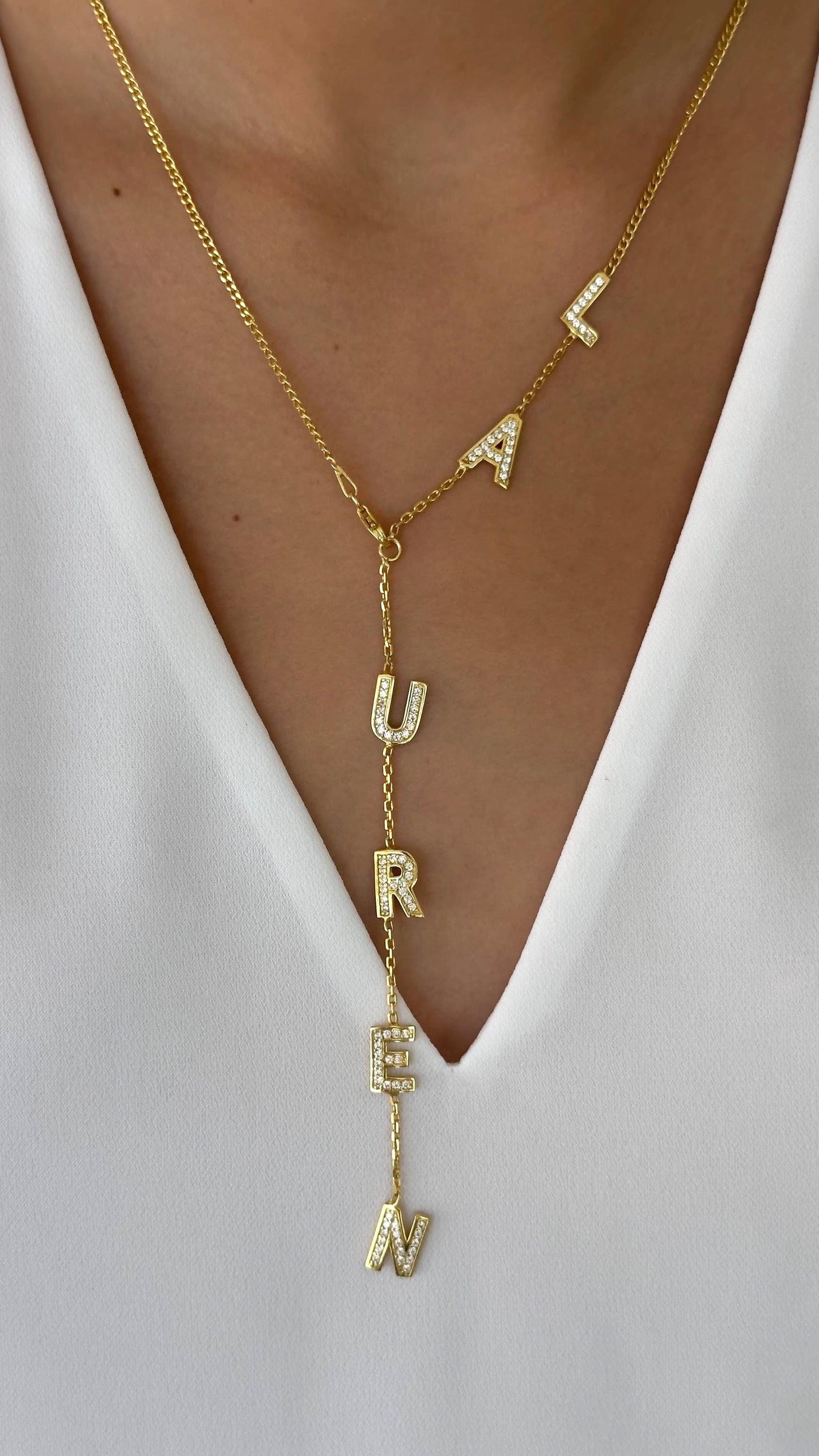 Model wearing gold personalized Y-drop lariat name necklace with sparkling cubic zirconia letters.