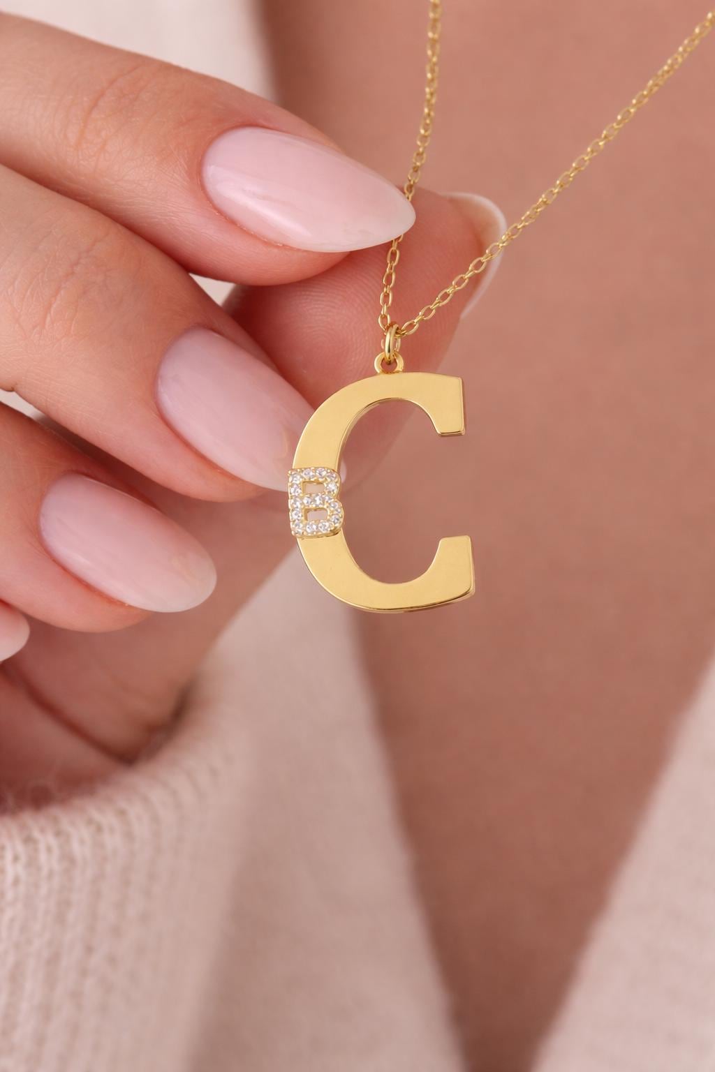 Large gold letter necklace featuring sparkling diamond like cubic zirconia accent