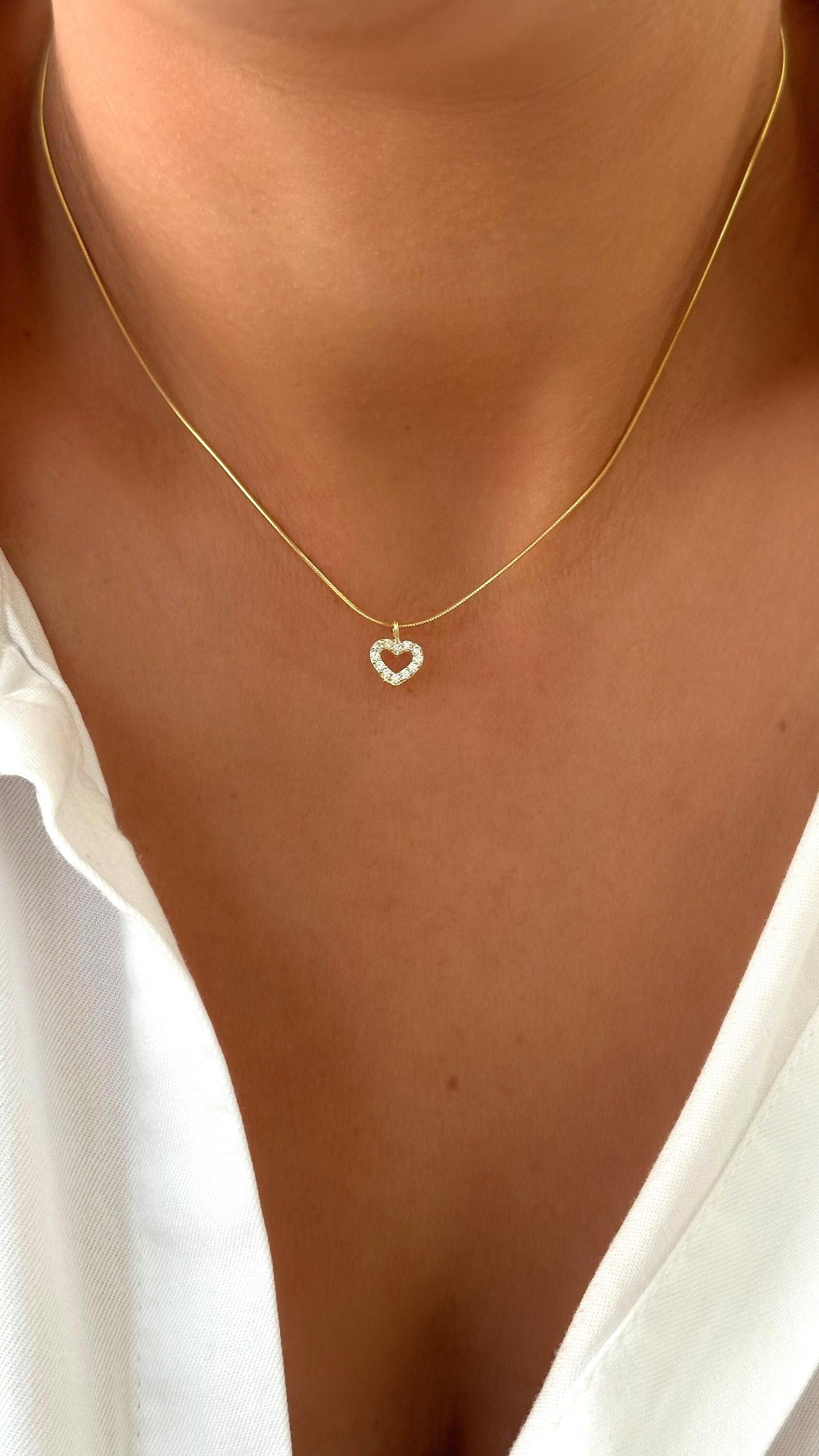Model wearing gold plated heart necklace with tiny cubic zirconia gemstone, minimalist wedding jewelry.
