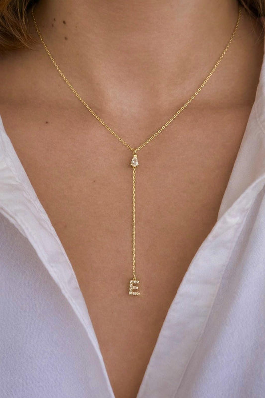 Dainty gold lariat initial necklace worn by woman, minimalist personalized drop letter necklace with CZ stone elegant everyday jewelry