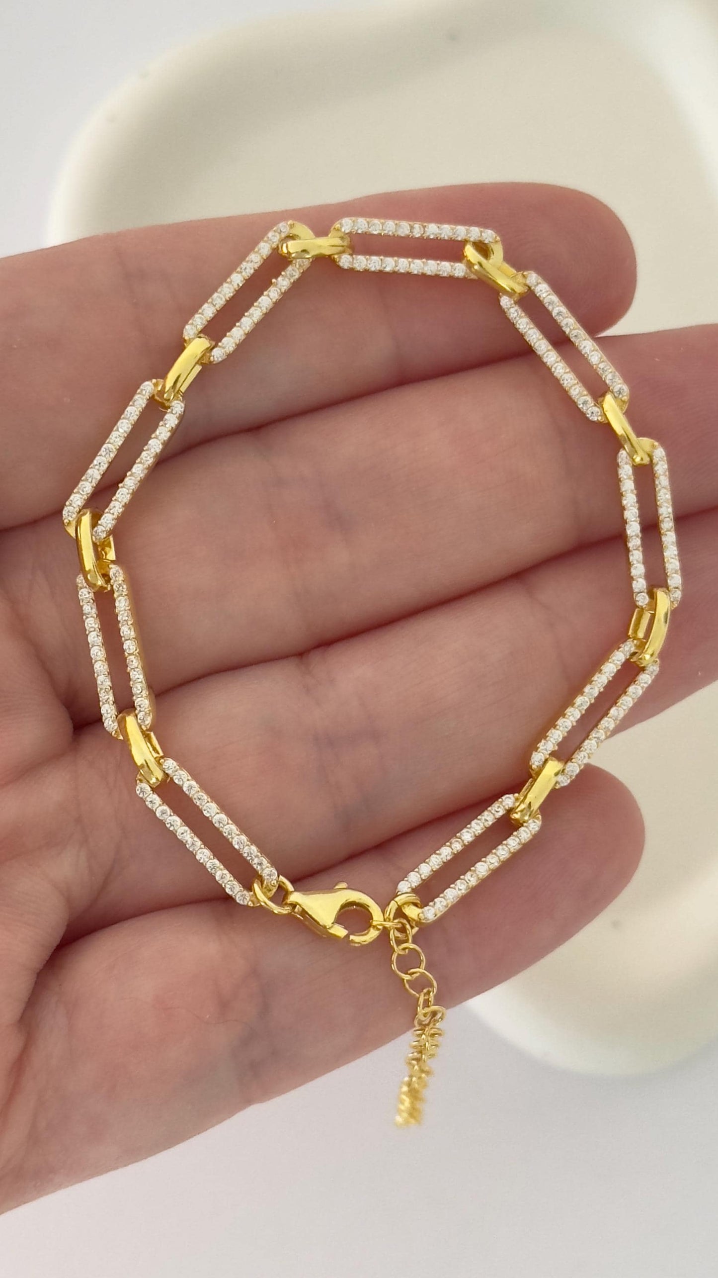 May include: A gold chain bracelet with small clear cubic zirconia stones set in the links. The bracelet has a lobster claw clasp and a small extension chain. 14k Gold Plated 925 Sterling Silver