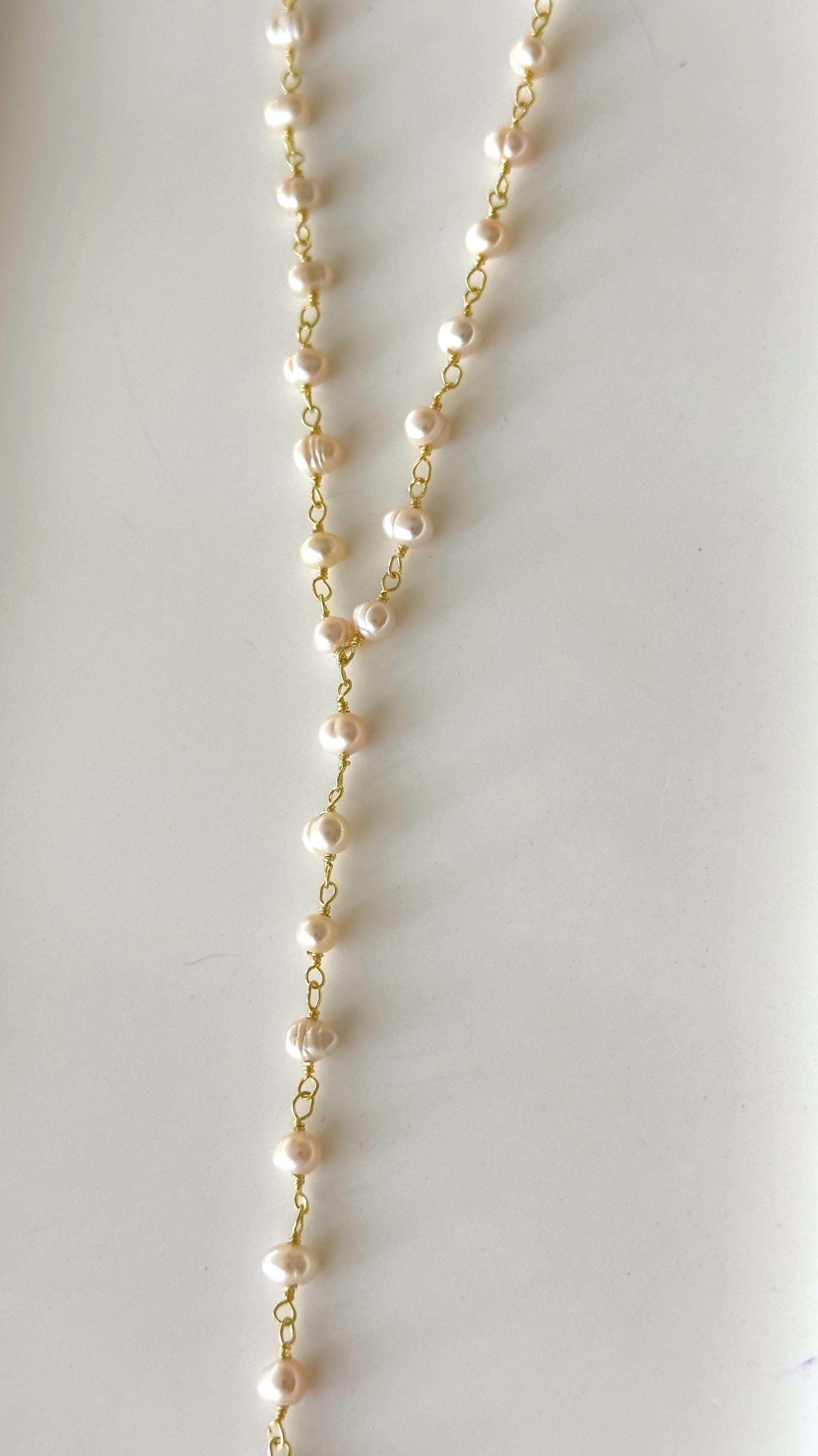 Elegant pearl lariat necklace with thin gold chain, minimalist jewelry close-up