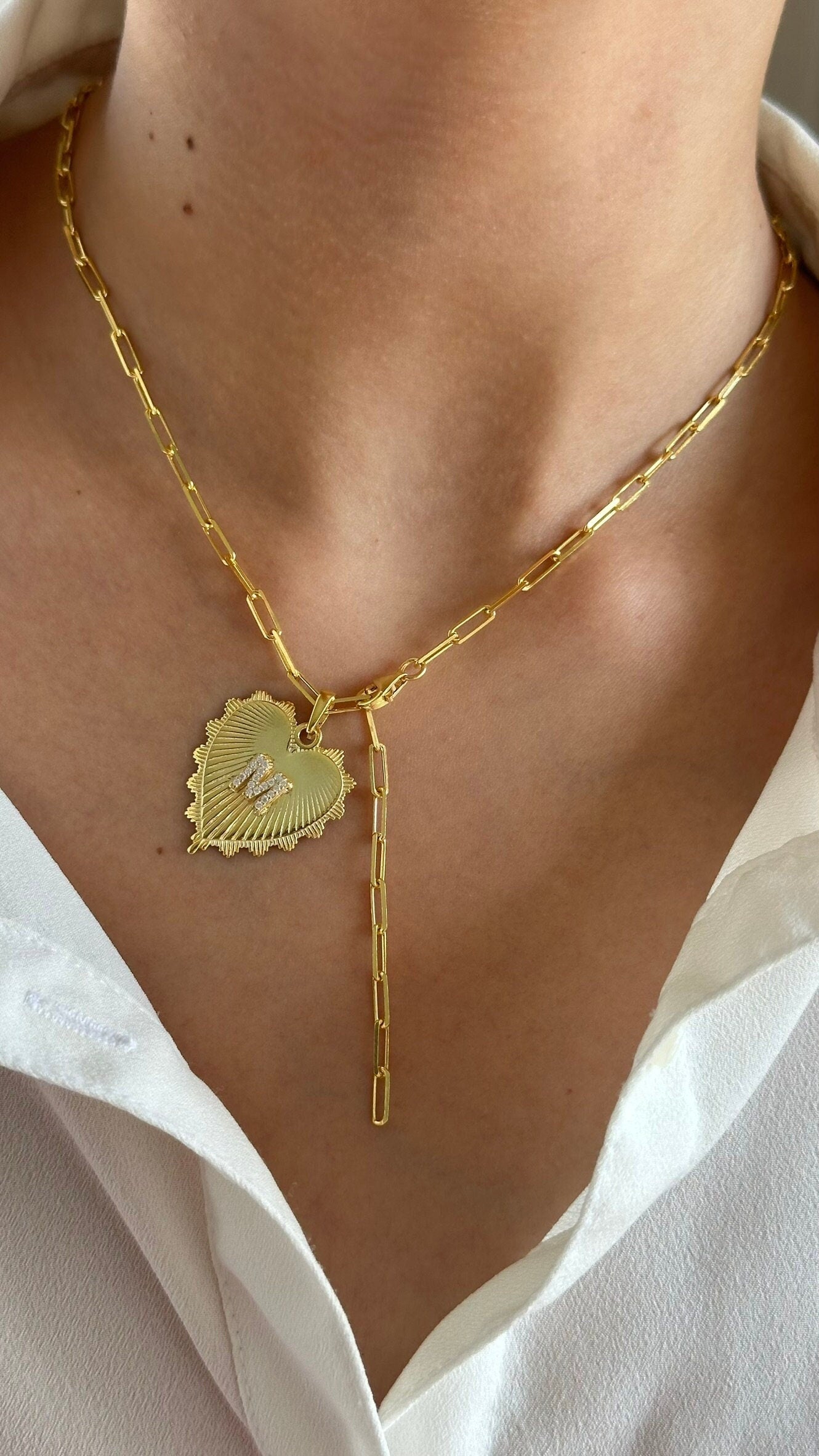 May include: A Lariat gold link chain necklace with a heart pendant. The heart pendant has a scalloped edge and is adorned with small, clear Letter initial cz gemstone  stones. The medallion pendant features the letter 'M' in the center. 925 Sterling Silver Jewelry Gifts