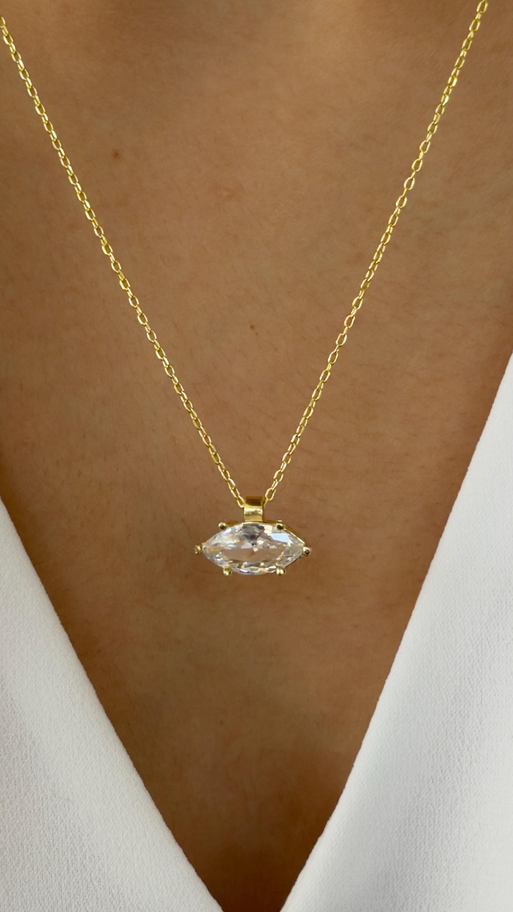 Dainty gold solitaire diamond pendant necklace layered on model.