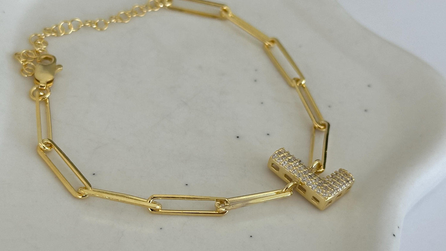 CustomBubble Letter link chain bracelet with a pave-set initial charm. The bracelet features a delicate gold chain with a secure clasp. The initial charm is a letter 'L' crafted from gold and adorned with sparkling cubic zirconia stones.  The bracelet is a stylish and elegant piece of jewelry, perfect for adding a touch of sophistication to any outfit.