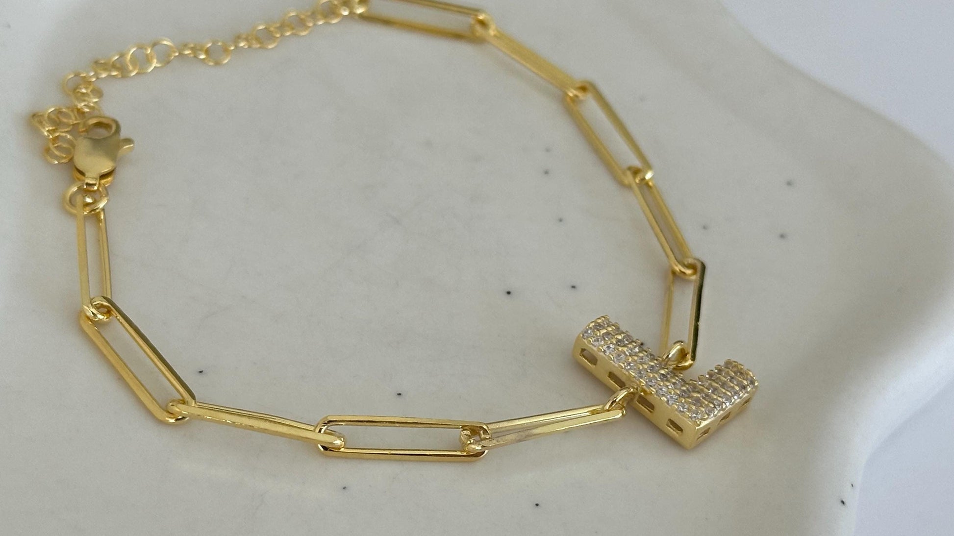 CustomBubble Letter link chain bracelet with a pave-set initial charm. The bracelet features a delicate gold chain with a secure clasp. The initial charm is a letter 'L' crafted from gold and adorned with sparkling cubic zirconia stones.  The bracelet is a stylish and elegant piece of jewelry, perfect for adding a touch of sophistication to any outfit.