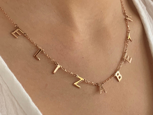 Gold necklace with a name spelled out in individual letters. The letters are hanging from the chain and spell out the name "Elizabeth". Personalized Name necklace 925 Sterling Silver 14k Gold Plated