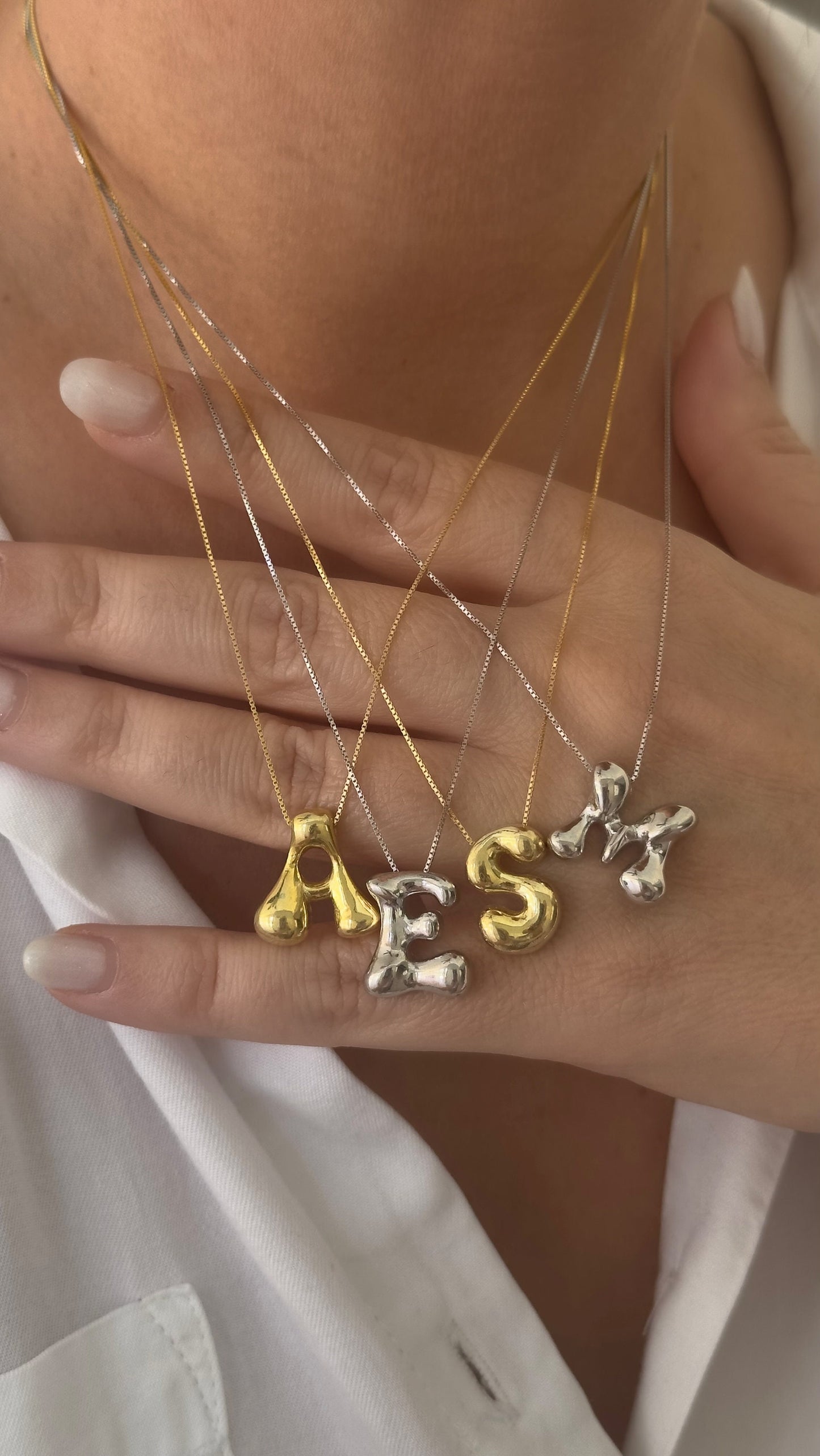 Trendy bubble letter necklace worn layered
