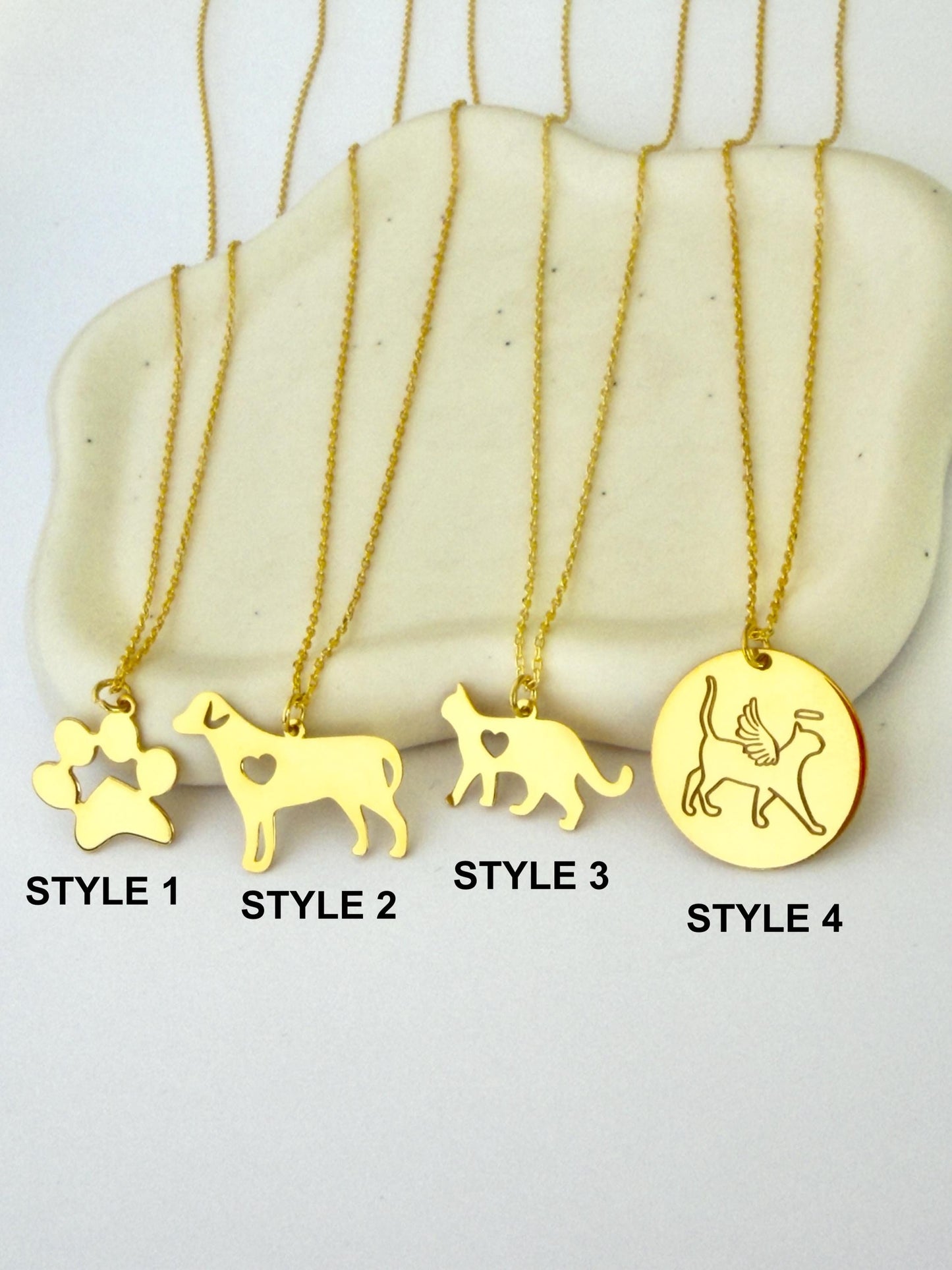 Gold dog cat paw necklaces on marble display