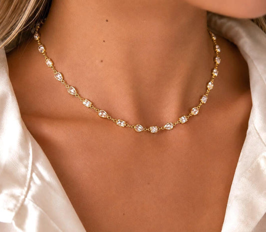 Gold crystal station necklace with clear cubic zirconia mix cut gemstones worn on a woman model, elegant layering necklace and bridal jewelry gift.