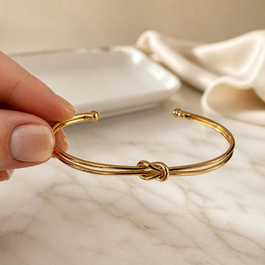 Double wire knot cuff bracelet shown by hand to highlight the polished finish and flexible open cuff design.