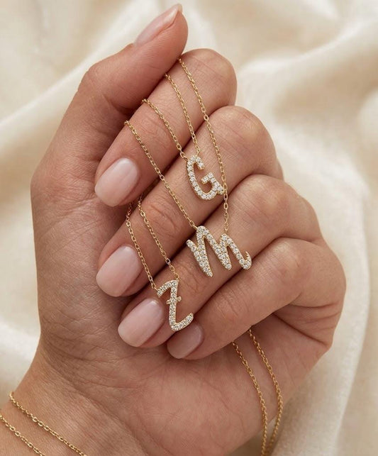 Personalized gold diamond initial necklaces with sparkling C, M and Z letter pendants displayed by hand, dainty custom jewelry and meaningful gift for girlfriend, daughter or best friend.
