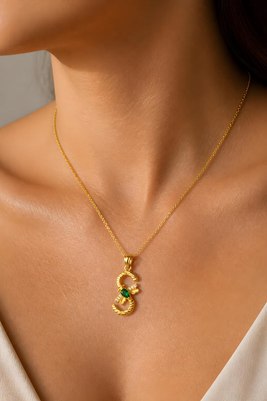 Birthstone initial necklace with gold letter S pendant, green birthstone and crystal bee accent, shown worn as personalized sterling silver jewelry for women.