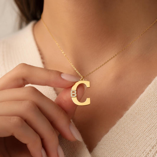 Close-up of a woman wearing a Double Initial Necklace with a personalized gold letter pendant and sparkling CZ diamond initial in Solid 925 Sterling Silver, meaningful personalized jewelry, gift for her.