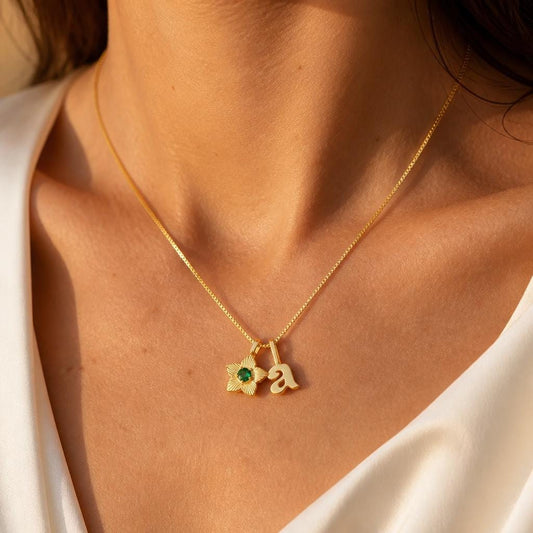 Personalized initial birthstone necklace with gold flower charm and green birth month stone on model